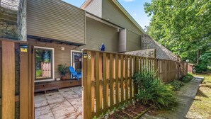 A residential property with a wooden fence, a patio with outdoor furniture, and a house with a beige exterior.