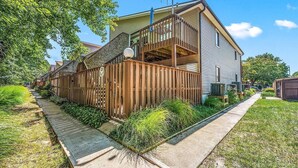 A two-story house with a wooden deck and a covered outdoor area.
