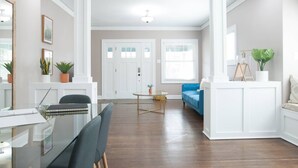 A spacious living room with a blue sofa, a glass coffee table, and a white fireplace. - Adorable Remodeled Broadripple home walking distance to bars and restaurant.  (Indianapolis)