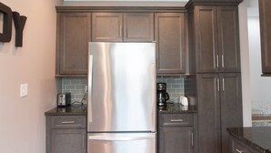 A kitchen with dark wooden cabinets, a stainless steel refrigerator, a coffee maker, and a toaster. - Adorable Remodeled Broadripple home walking distance to bars and restaurant.  (Indianapolis)