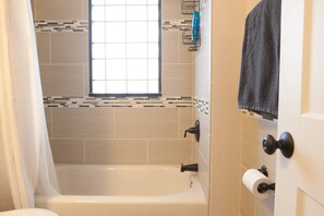 Een bad/douchecombinatie, een haardroger, handdoeken, zeep