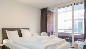 Habitación de hotel moderna con una cama grande, una silla y vistas al exterior.
