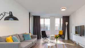 Una sala moderna con sofá, mesa de centro, televisor y vistas al balcón.