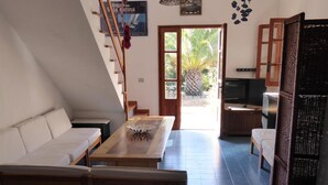 A modern kitchen with a wooden table, a sofa, and a staircase leading to a balcony. - Villa nestled in the countryside with spectacular views for 6 people (Carloforte)