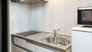 A modern kitchen with a stainless steel sink, a built-in microwave, and a range hood. - GRAND BASE Hakata (Fukuoka)