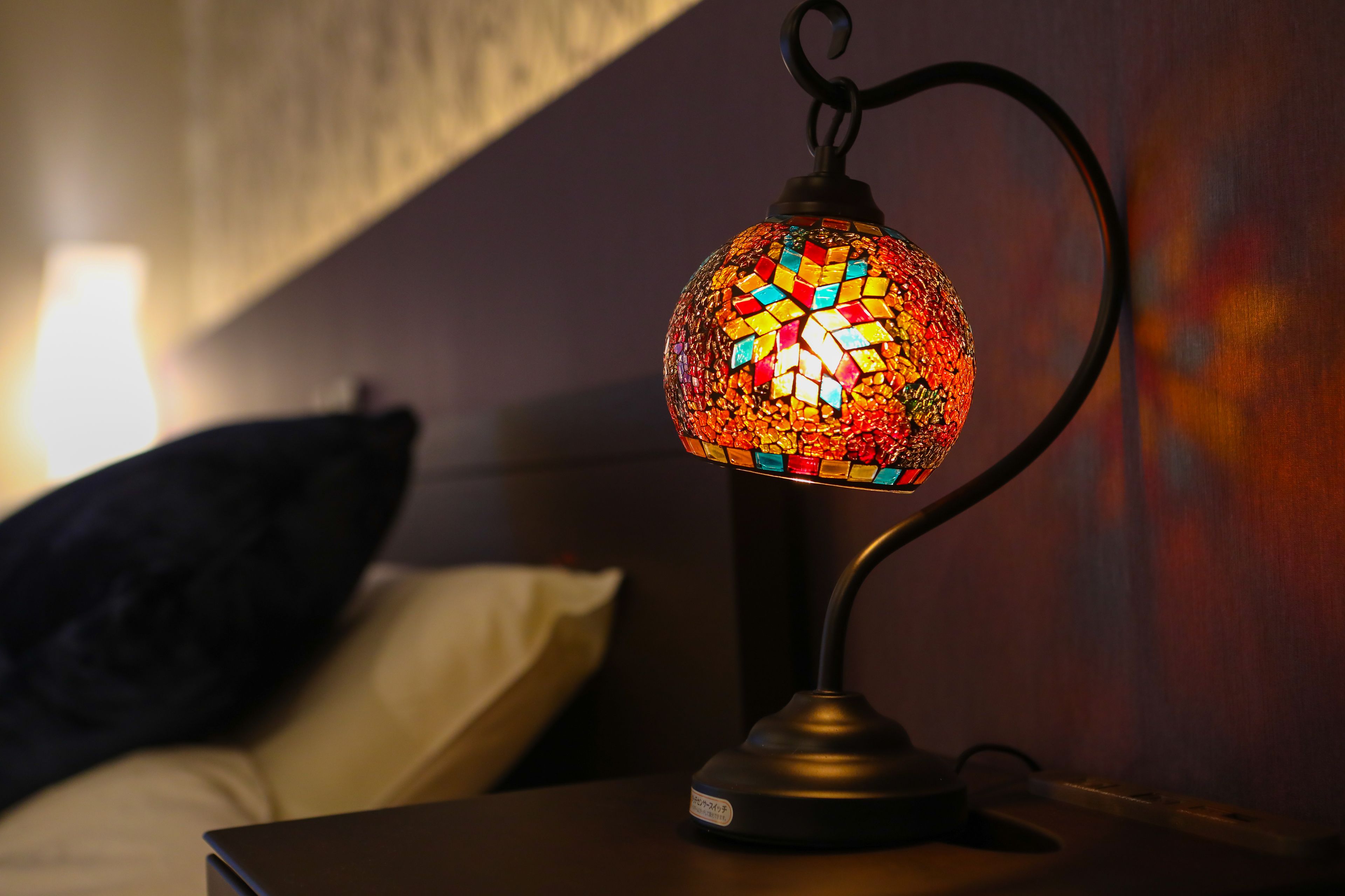 A mosaic lamp on a bedside table in a dimly lit room.