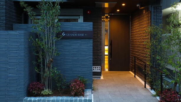 A modern hotel entrance with a sign reading "GRANDE BASE". - GRAND BASE Hakata (Fukuoka)
