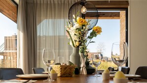 A dining table with a vase of flowers, wine glasses, and a basket of bread. - Eagle 8p - Four Bedroom Villa, Sleeps 8 (Oosterhout)