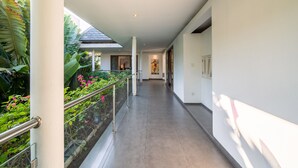 A corridor with a glass railing, a tiled floor, and a view of a building with a sloped roof. - Private Pool Villa | Daily Housekeeping | Seminyak (Seminyak)