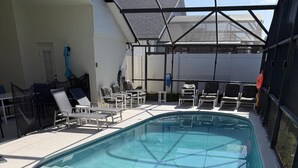 Une piscine avec des chaises longues et un espace abrité.