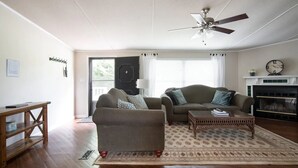 Ein Wohnzimmer mit Sofa, Sesseln, Couchtisch und Kamin.
