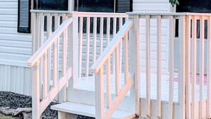 Eine weiße Holztreppe führt zu einer Terrasse mit Geländer.