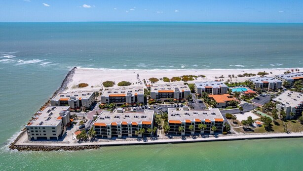 Luchtbeeld van een kusthotel met meerdere gebouwen, een strand en een zwembad.