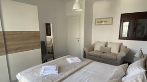 Une chambre à coucher avec un lit, un canapé, une chaise et une lampe.