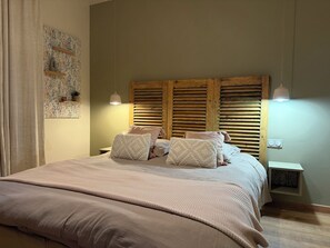 Un dormitorio con una cama grande, cabecera de madera, mesitas de noche y estantes en la pared.