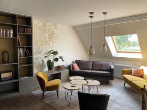 A modern living room with a bookshelf, a sofa, a yellow armchair, a coffee table, and a skylight.