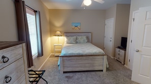 Quarto com cama, mesa de cabeceira, abajur, cômoda, cadeira e televisão.