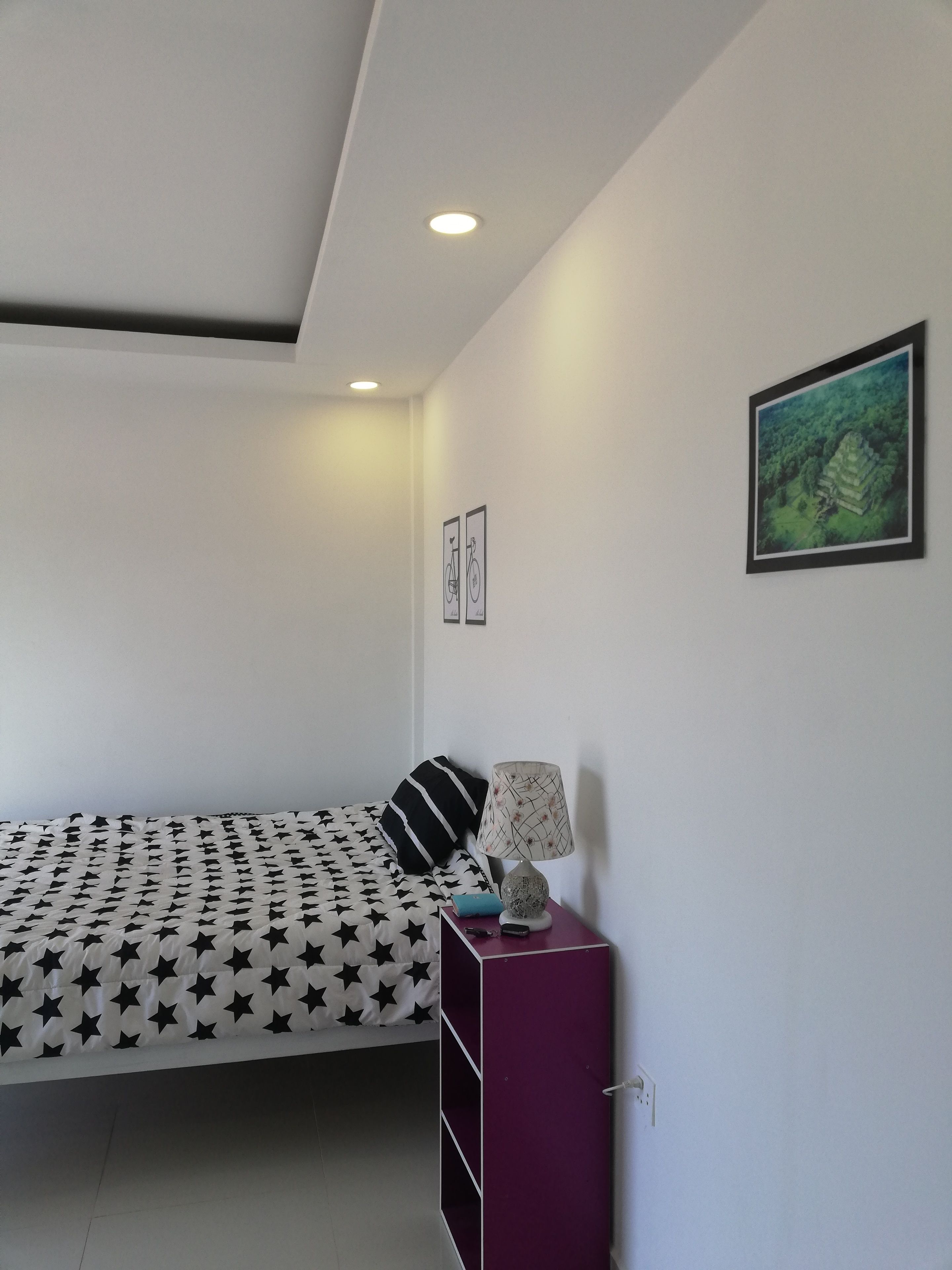 A bedroom with a bed, a nightstand, a lamp, and a framed picture on the wall.