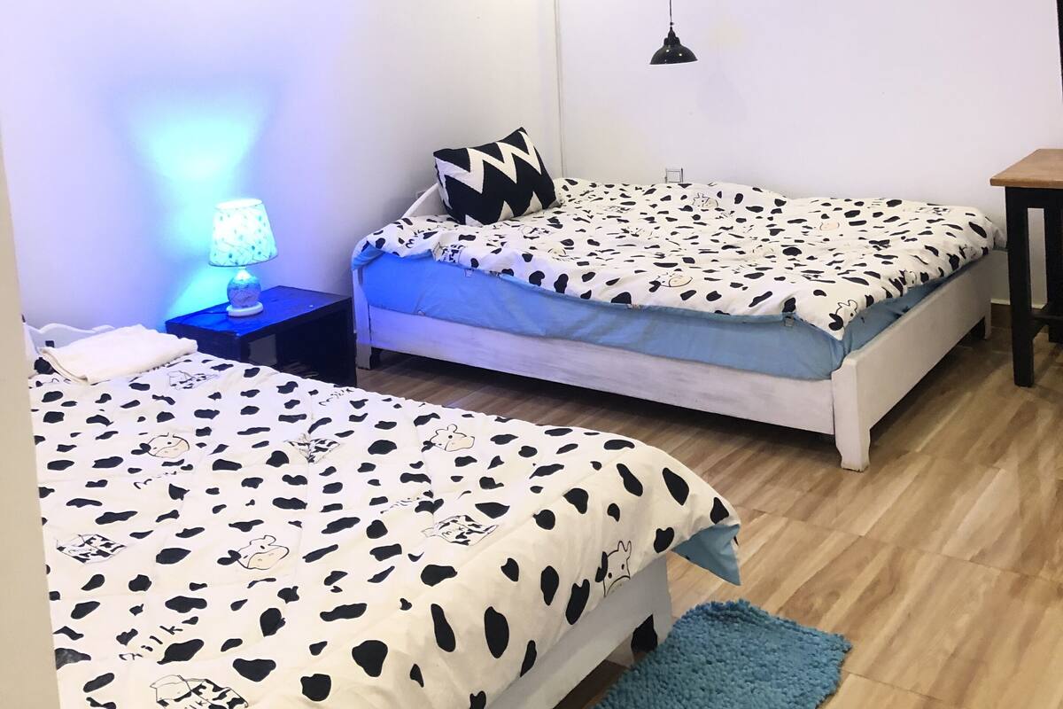 A room with two beds, a desk, a lamp, and a motivational poster on the wall.