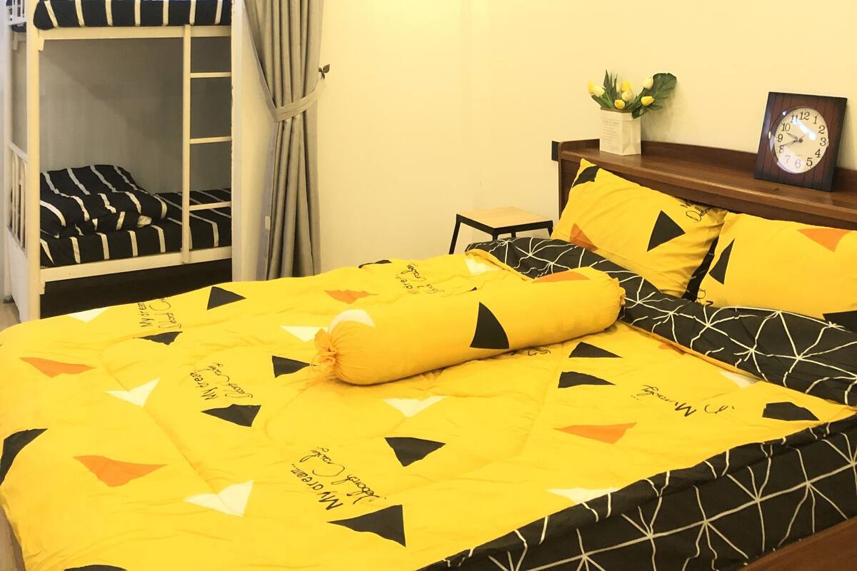 A bedroom with a bunk bed, a bedside table with a clock, and motivational wall art.