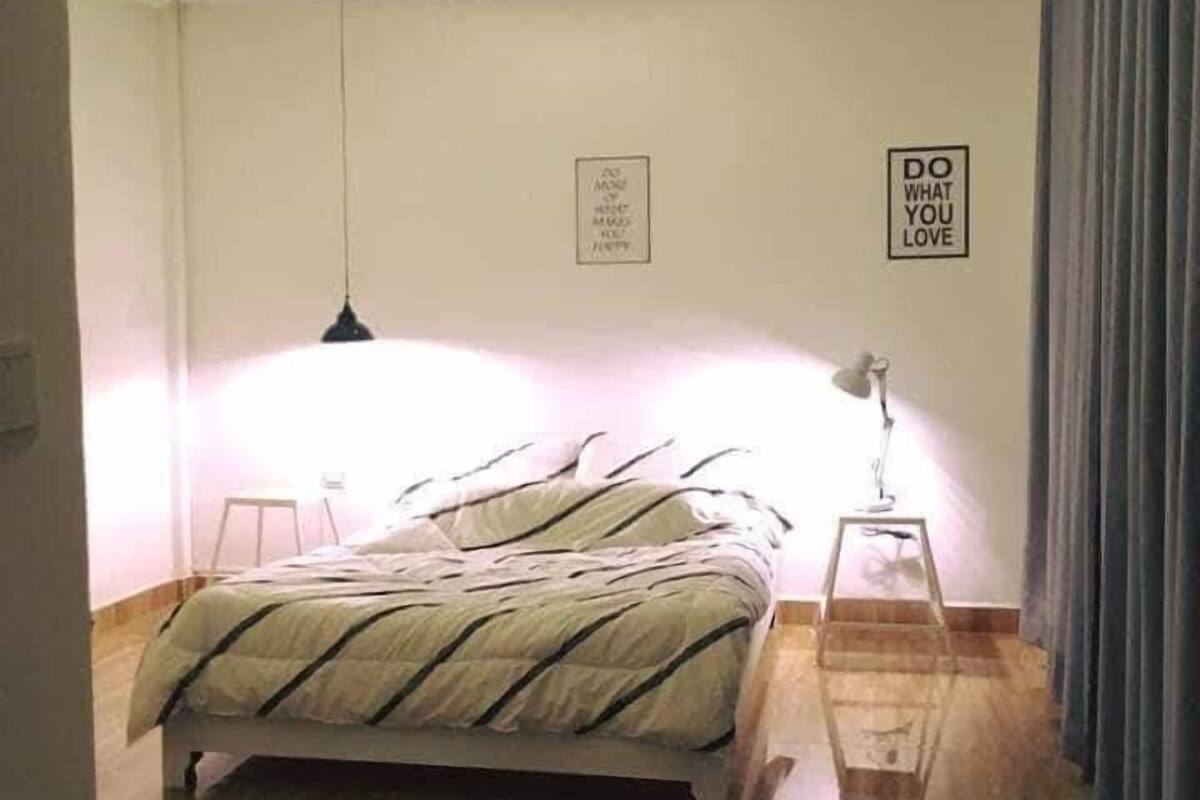 A bedroom with a bed, a standing lamp, and two wall-mounted signs.