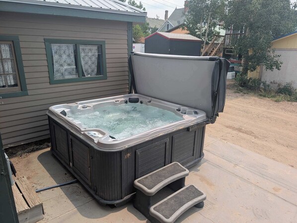 A hot tub with steps, a house with a window, and a tree. - The Governor's Mansion — 6BR Sleeps 14, 3 Private Units, Hot Tub, Sauna (Leadville)
