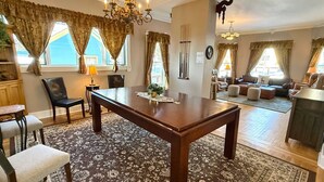 Un vaste salon agrémenté d’une table basse en bois, un coin repas avec une table et des chaises, et un espace détente avec des canapés et des poufs.