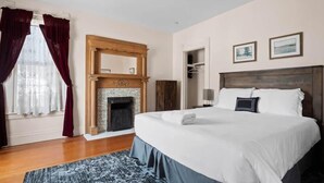 Une chambre d’hôtel avec un grand lit, une cheminée, une armoire et un miroir.