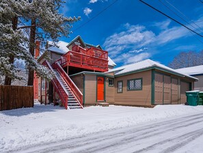 A two-story building with a red staircase and a red door, surrounded by snow. - The Governor's Mansion — 6BR Sleeps 14, 3 Private Units, Hot Tub, Sauna (Leadville)
