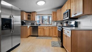 Une cuisine moderne avec des meubles en bois, des appareils électroménagers en acier inoxydable et une fenêtre qui laisse entrer la lumière naturelle.