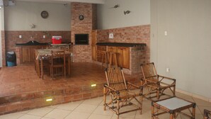 A spacious kitchen with a brick backsplash, wooden cabinets, and a dining area with bamboo chairs.