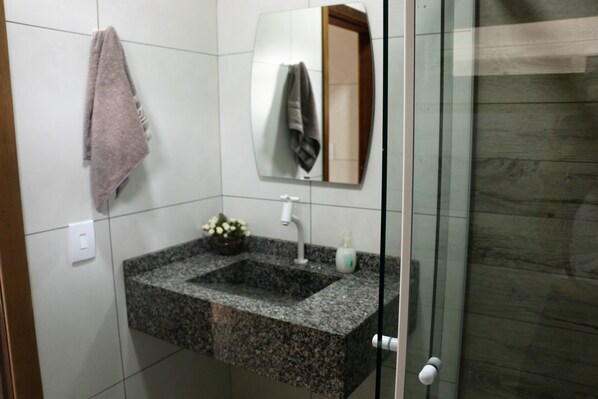 A bathroom with a granite sink, a mirror, a towel, and a small plant.