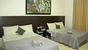 A hotel room with two beds, a nightstand, a TV mounted on the wall, and a window with curtains.