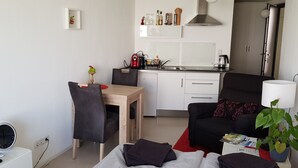 Een knus woongedeelte met een kitchenette, een eethoek en een zithoek met een bank en salontafel.