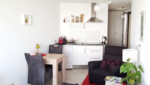 Een compacte leefruimte met kitchenette, een eethoek en een zithoek.