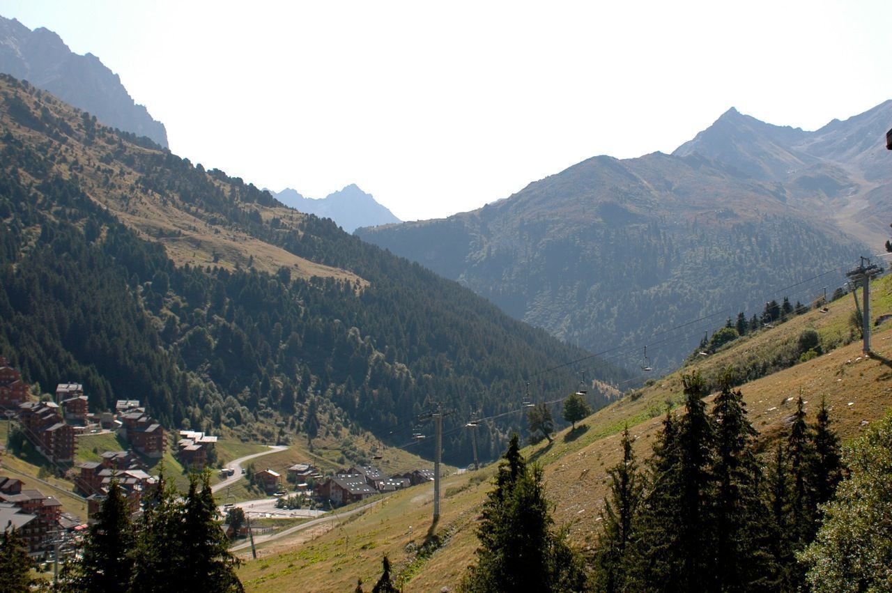 A mountainous landscape with a small village, houses, and a ski lift.