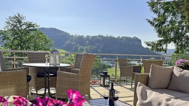 An outdoor patio with wicker furniture, a table, and a bottle of wine. - Vulkaneifel Type L-A4 (Gerolstein)