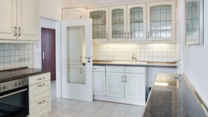 Una cocina moderna con armarios blancos, horno empotrado y un amplio ventanal.