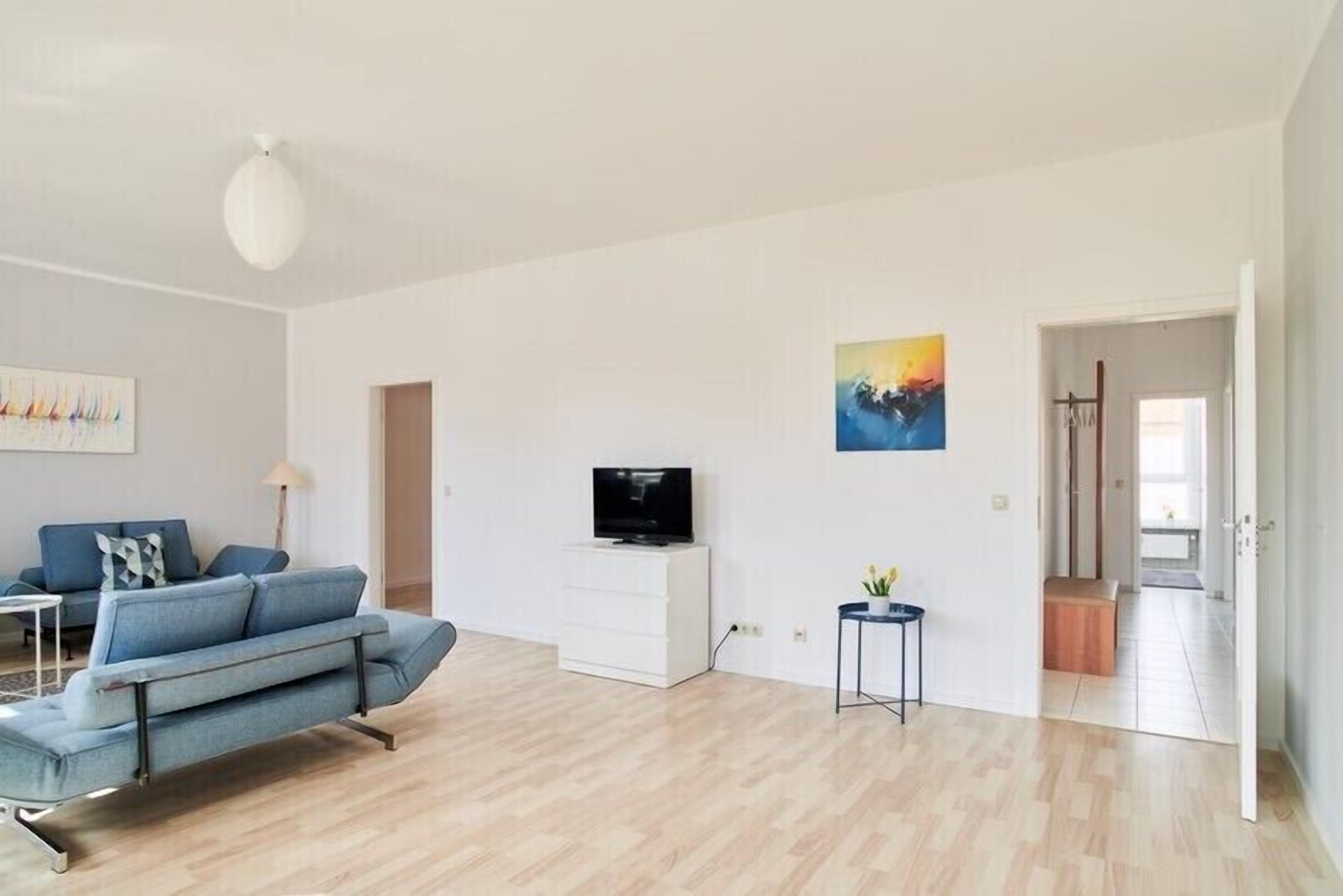 A modern living room with a sofa, a TV, and a painting on the wall.