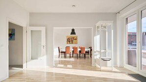 Un amplio comedor con suelo de madera en espiga, una mesa con sillas e iluminación colgante.