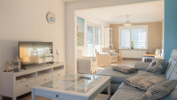 Una sala de estar moderna con una mesa de centro de vidrio, un sofá y un televisor.