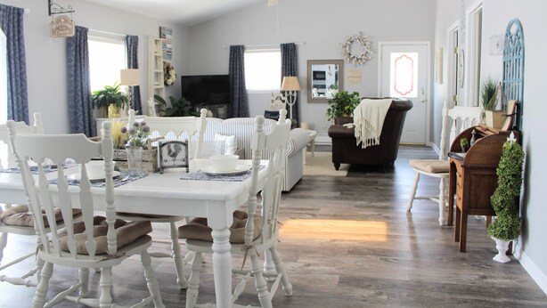 A dining area with a white table and chairs, a sofa, and a television in the background. - Unique Farm Cottage, Close to City Feels like Country, One of a Kind! (Colorado Springs)