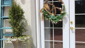 A white door with a gold doorknob, a window with blue shutters, and a potted plant with trailing vines. - Country Cottage Cross the Creek, Close to City Feels like Country, One of a Kind (Colorado Springs)