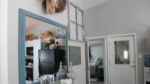 A hallway with a mirror, a door, and a small table with decorative items. - Unique Farm Cottage, Close to City Feels like Country, One of a Kind! (Colorado Springs)