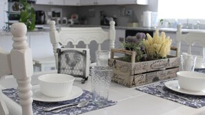 A dining table set with white plates, bowls, and a glass. There is a vintage-style clock and a crate with flowers on the table. - Unique Farm Cottage, Close to City Feels like Country, One of a Kind! (Colorado Springs)