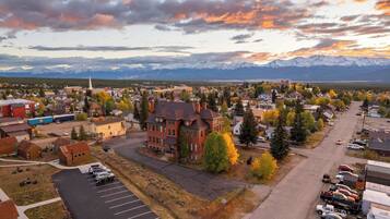 A town with a prominent red building, a parking lot, and a mountainous backdrop.