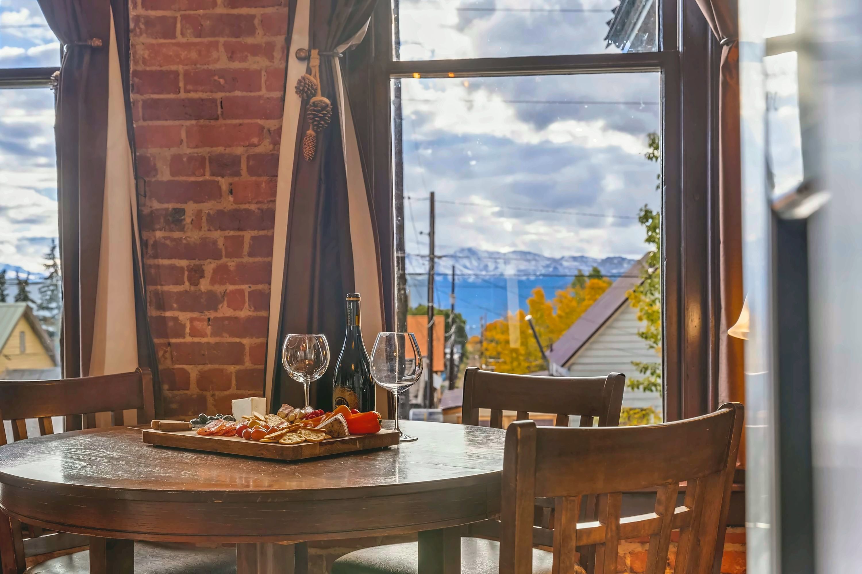 A dining table with a view of mountains and a lake through a window.
