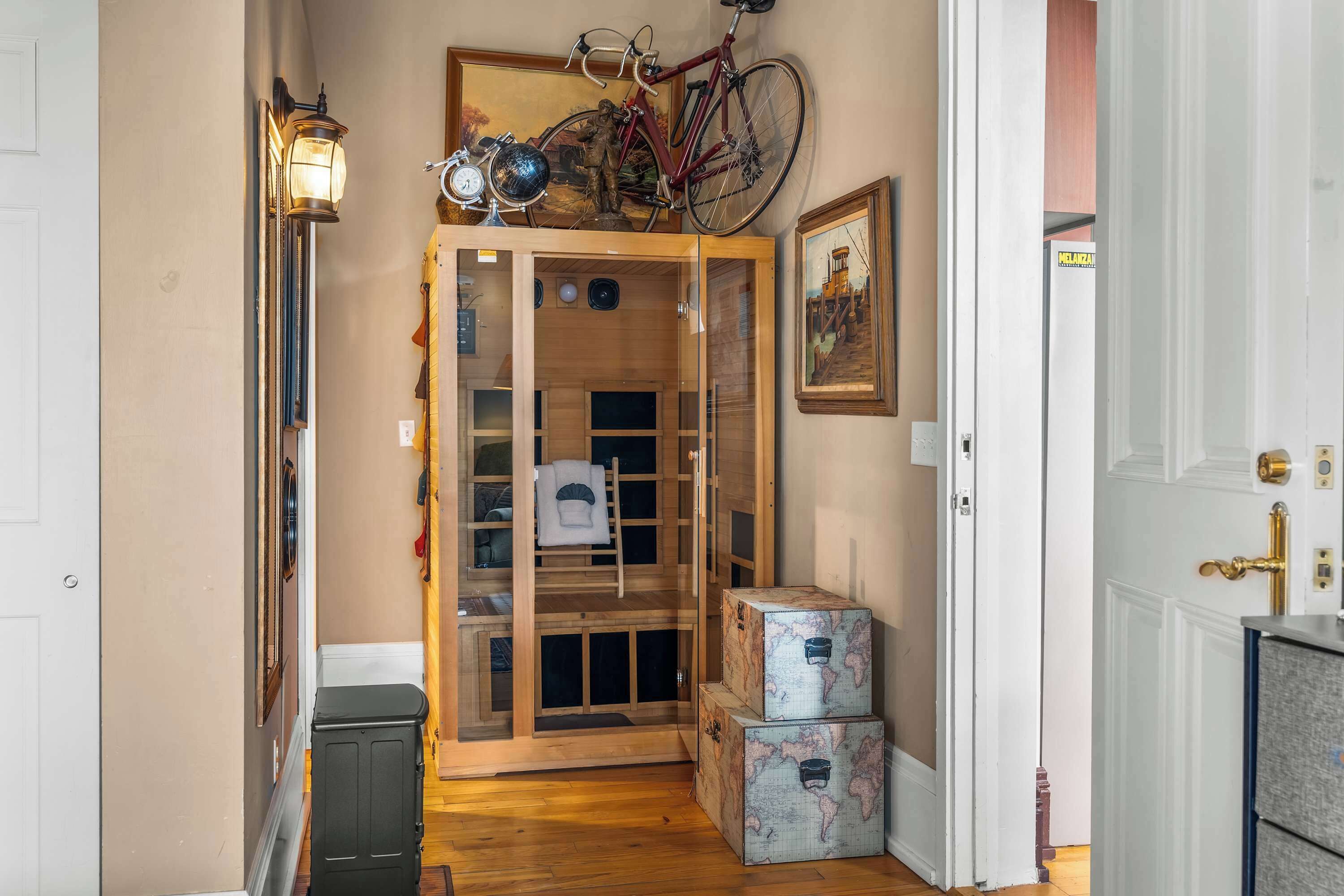 A wooden door with a bicycle and a globe on top, a globe on the wall, and a suitcase on the floor.