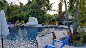 Ein Poolbereich mit Liegestuhl, überdachter Sitzgruppe und einem Hund in der Nähe des Pools.