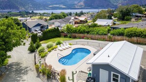 Zona residencial con piscina rodeada por una valla de madera, casas y montañas al fondo.